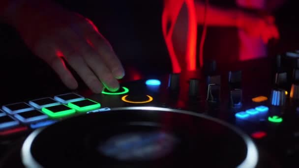Una persona que trabaja en un reproductor de color j. Clip. DJ crea música pulsando botones y deslizamiento slipmat. — Vídeo de stock