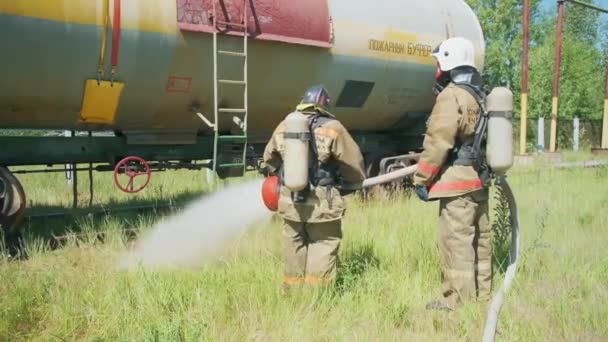 Hasiči u výstroje. Klip. Dva muži používají obrovský proud vody ke kontrole požární techniky. — Stock video