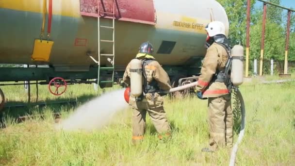 Пожарные возле оборудования. Клип. Двое мужчин используют огромный струй воды, чтобы проверить пожарное оборудование. — стоковое видео