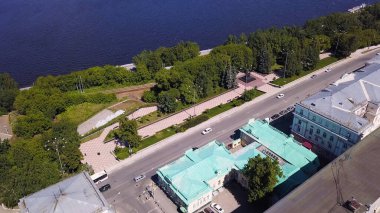 Kuşbakışı fotoğraf. Şarjör. Nehir manzaralı güzel şehir manzarası, orman, evler ve arabalı bir yol..