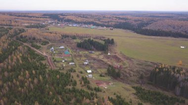 Sonsuz bir sonbahar ormanı ve bir köyün manzaralı panoramik manzarası. Şarjör. Kırsal alan, karışık orman, kırsal bir köyün geleneksel evleri, yaşamak için ekolojik bir yer..