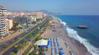 İnsansız hava aracı. Şarjör. Güzel bir okyanusun üzerinde uçmak ve plajı, arabaları, trafik sıkışıklığı ve büyük evleri olan büyük bir tatil köyü.