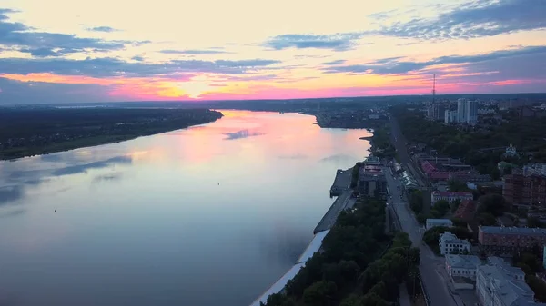 Hermosa vista de la ciudad desde una vista de pájaro. Clip. Una elegante puesta de sol colorida con casas y un río tranquilo. Tranquilidad urbana . — Foto de Stock