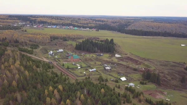 Sonsuz bir sonbahar ormanı ve bir köyün manzaralı panoramik manzarası. Şarjör. Kırsal alan, karışık orman, kırsal bir köyün geleneksel evleri, yaşamak için ekolojik bir yer..