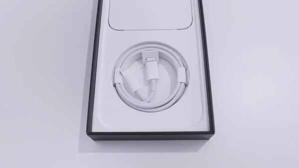 Ottawa, Canadá - 11.24.2020 caja abierta de un iPhone de Apple sobre un fondo de mesa blanco. Acción. Vista superior de un cable de carga blanco dentro de la caja del teléfono inteligente. — Foto de Stock