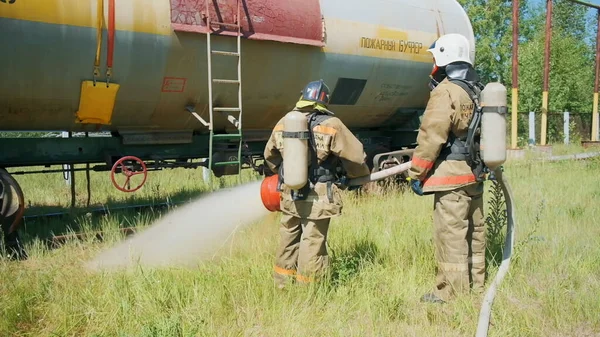 Pemadam kebakaran dekat peralatan. Jepit. Dua orang menggunakan jet besar air untuk memeriksa peralatan api. — Stok Foto