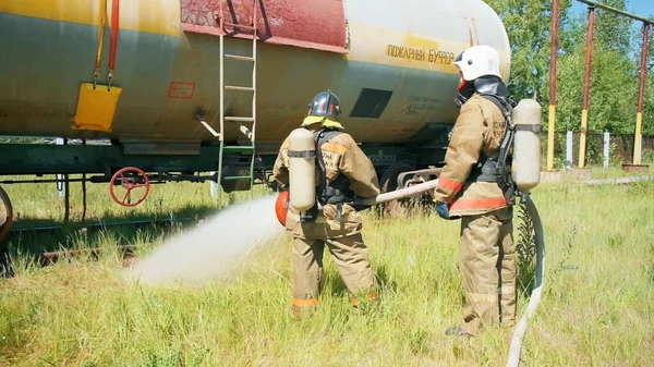 Feuerwehrleute in der Nähe des Gerätes. Clip. Zwei Männer kontrollieren mit einem riesigen Wasserstrahl die Brandausrüstung. — Stockfoto
