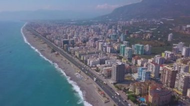 İnsansız hava aracından dağ manzaralı büyük bir şehir. Şarjör. Sahile yakın bir tatil köyü ve parlak bir gökyüzünün üzerinde kocaman mavi bir okyanus..