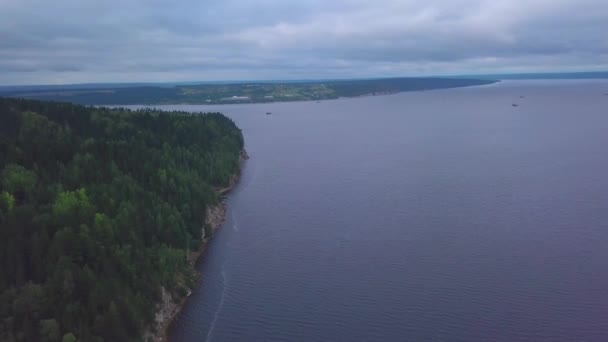 Vue aérienne de la falaise escarpée au-dessus de la surface calme de la rivière. Clip. Forêt de pins verts sur les collines et la surface de l'eau. — Video