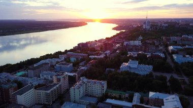 İnsansız hava aracından güzel bir manzara. Şarjör. Gün batımında şehir nehri ve büyük şehir evleri