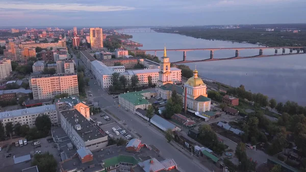 Der Blick aus der Drohne. Clip. Eine schöne Abendstadt in Russland mit einer Brücke, einem Fluss und Häusern vor nebligem Himmel — Stockfoto
