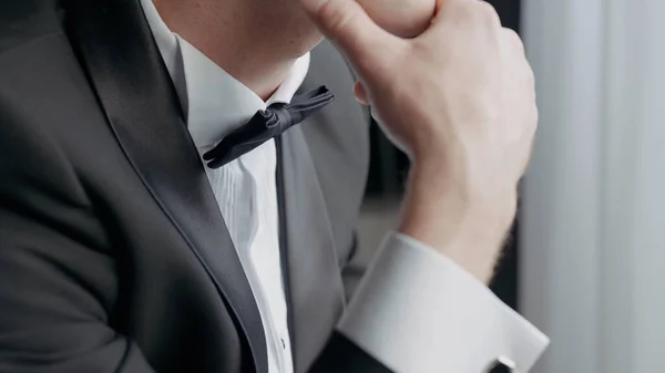 Close up de um homem vestido com um terno preto e branco com um laço. Acção. Detalhes de um noivo masculino preocupado antes da cerimônia de casamento. — Fotografia de Stock