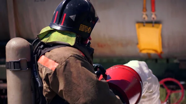 Arbeitsabläufe. Clip. Feuerwehrleute in Uniform kontrollieren die Ausrüstung und gießen Schaum und Wasser ab. — Stockfoto