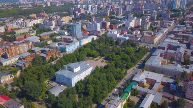 Helikopterden şehir manzarası. Clip. Bir park alanının yanında duran büyük evler ve büyük yeşil ağaçlar ve yakınlarda bir yol..