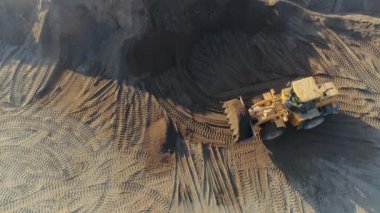 İnşaat alanında çalışan makinelerin havadan görüntüsü. Sahne. Buldozer ve kamyon kumla çalışıyor..