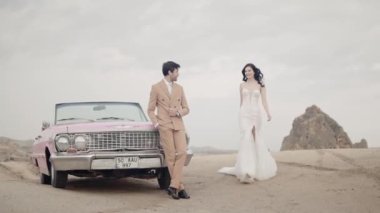 Kapadokya 'daki bir dağın tepesinde fotoğraf çekilirken çok güzel genç bir çift. Başla. Cabriolet 'in pembe arabasının yanında romantik bir çift..