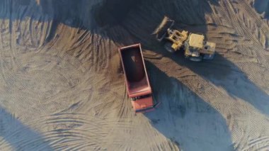 İnşaat alanında çalışan makinelerin havadan görüntüsü. Sahne. Buldozer ve kamyon kumla çalışıyor..