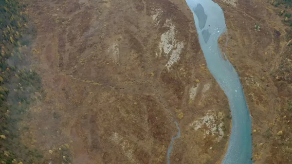 Natureza da altura de um drone. Clipe. O azul claro rio sinuoso ao lado da floresta cinza flui através das cadeias montanhosas. — Fotografia de Stock