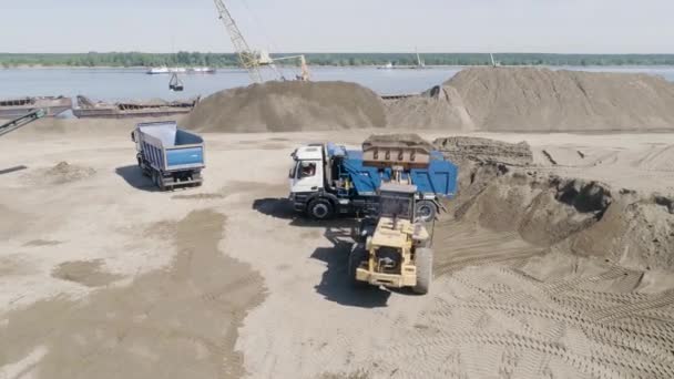 Grävmaskinen lastar lastbilen med sand och jord. På plats. Flygfoto av utrustningen förbereder byggarbetsplatsen för byggandet av en lägenhetsbyggnad. — Stockvideo