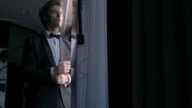 Pencerenin yanında duran endişeli bir damat. Başla. Düşünceli çekici koca düğün töreninden önce takım elbise giyiyor..
