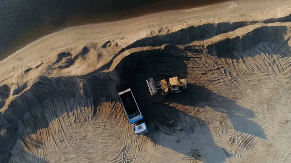 Těžba písku, těžba písku v lomu. Scéna. Letecký pohled shora na buldozer stroj uvedení písku na karoserii náklaďáku. — Stock fotografie