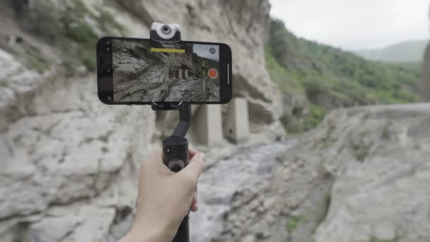 Shooting mountains and waterfalls. Action. The phone stands on a stand and shoots beautiful landscapes with mountains and a small dripping waterfall . — 图库视频影像