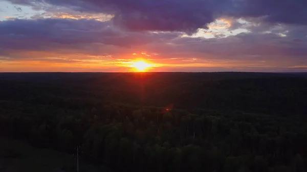 Spektakulärer Himmel von einer Drohne aus. Clip. Ein schöner heller Sonnenuntergang mit violetten und orangen Farbtönen, wo die Sonne über dem Wald zu sehen ist — Stockfoto