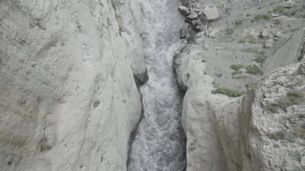 岩の側面の間に強力な水の流れが圧迫されています。行動だ。山の間の峡谷に流れる川の空中風景. — ストック動画