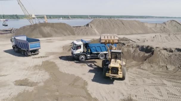 Excavator with dump truck on background of river. Scene. Top view of clearing of territory for construction. Construction machines for clearing territory on river bank — Vídeo de Stock