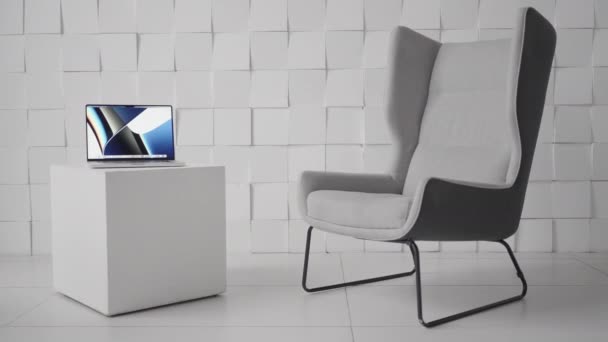 Laptop em uma mesa de café em forma cúbica em um escritório moderno. Acção. Design minimalista da sala com uma cadeira confortável e um computador em uma pequena mesa. — Vídeo de Stock