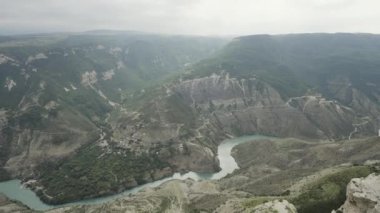 Dağların arasından akan ve ormanla kaplanmış dağ nehrinin havadan çekilmiş görüntüsü. Başla. Tepelerin ve akan nehirlerin vahşi doğal arka planı.