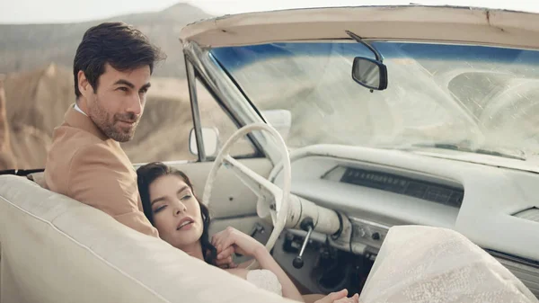 Schönes Paar im Cabrio. Handeln. Stilvolles Brautpaar posiert im Cabrio. Schönes verliebtes Paar im Auto vor dem Hintergrund der Schlucht — Stockfoto