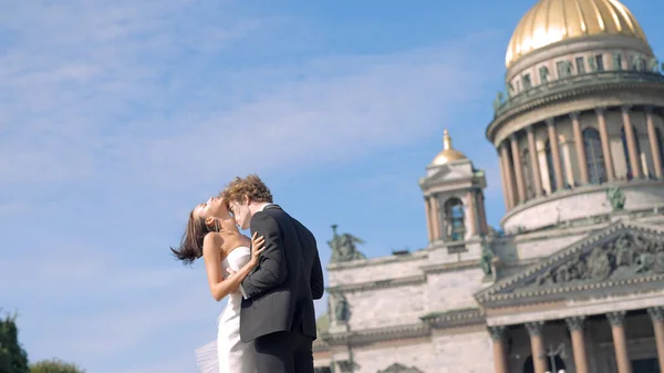 Photosession of a beautiful elegant wedding couple on the background of St. Isaac s Cathedral. Action. Loving Bride and groom embracing at the historical center of Saint Peterburg, Russia. — 图库照片