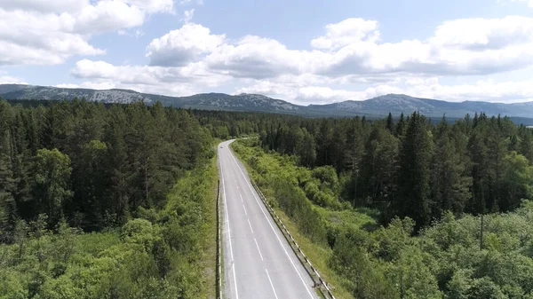 Top view of empty road in middle of forest. Scene. Panorama of highway passing through wooded area on background of mountains. Beautiful panorama of highway, green forest and mountains on horizon on — 图库照片