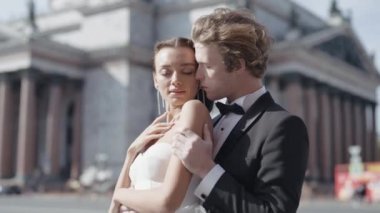 Şehrin arka planında kucaklaşan güzel yeni evliler. Başla. Şehir ortamında yeni evliler için fotoğraf çekimi. Güzel yeni evliler şehirde eski mimariyle kucaklaşır.