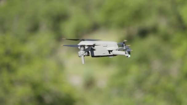 Flying drone in air. Action. Drone flies over green trees. New model of drone in air shoots green trees in summer — Stockvideo