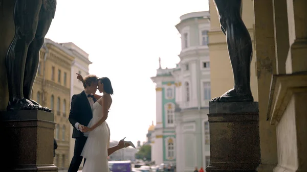 Photosession of a beautiful elegant wedding couple inside the porch of the New Hermitage by the feet of atlantes. Action. Loving Bride and groom embracing at the historical center of Saint Peterburg — Stockfoto
