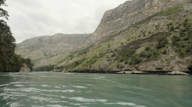 Turkuaz dağ nehri ormanla kaplı dağların arasından akıyor. Başla. Tepelerin ve akan nehirlerin vahşi doğal arka planı.