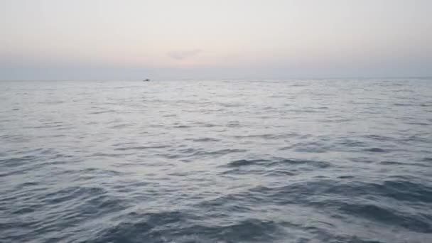 美丽的大海行动。海面上波涛汹涌的大海，背景是薄薄的天空，船尾在远方航行. — 图库视频影像