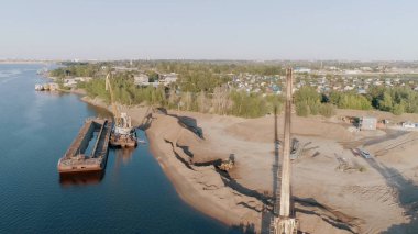 Sahilde inşaat var. Başla. Büyük ekipmanlar ormanın ve şehrin yanına büyük bir kamyon ve denizin yanında bir gemi inşa eder..