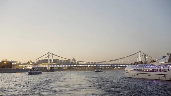 Köprü ve ışıklarla güzel bir gün batımı manzarası. Başla. Dalgalanan nehri geçen gemiler, turizm konsepti.. — Stok fotoğraf