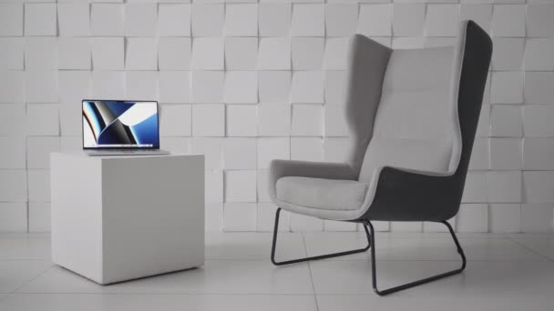 Comfortabele werkplek. Actie. Een prachtige plek met een witte fauteuil en een kleine tafel met een computer zonder mensen. — Stockvideo