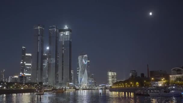 Moscow 2021. Action. Beautiful huge evening buildings near the river in Moscow were shot from afar on a dark evening with bright lights and lanterns that glow . — Stock Video