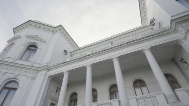 Beyaz yüzlü güzel, eski bir bina. Başla. Mavi gökyüzünün arka planında güzel beyaz bir malikane. Yazın şehrin dışındaki güzel beyaz bina