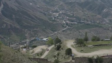 Aerial view of a helicopter flying above the small village located in mountains. Action. Hilly region with the residential settlement.