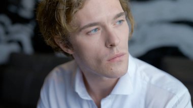 Uzun saçlı yakışıklı bir adam dinleniyor. Motor. Yakışıklı damat dinleniyor ve kanepede bir fincan kahve içiyor..