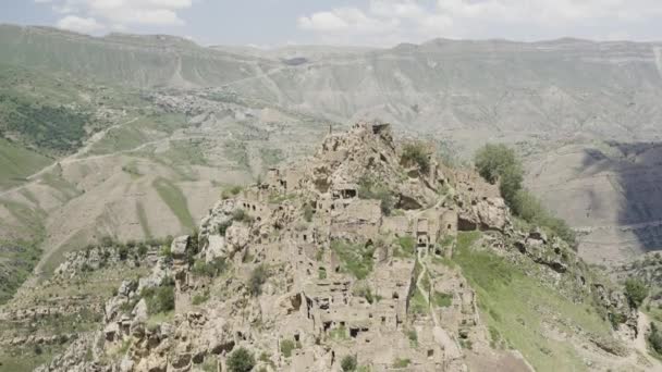 Ruinen eines alten Dorfes mit verlassenen Steinmauern an einem Berghang. Handeln. Sommerfelsen und Wohnsiedlung in der Nähe des Felsens vor bewölktem Himmel. — Stockvideo