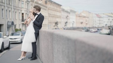 Şehrin arka planında kucaklaşan güzel yeni evliler. Başla. Şehir ortamında yeni evliler için fotoğraf çekimi. Güzel yeni evliler şehirde eski mimariyle kucaklaşır.