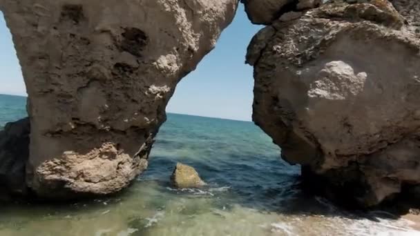 Vista aérea de rocas y playa de arena, verano y concepto de vacaciones. Acción. Volando a través del arco de piedra con el océano sin fin detrás del horizonte. — Vídeos de Stock