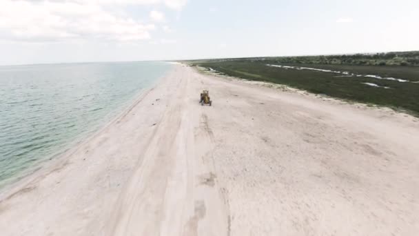 Flygfoto av en traktor på den tropiska stranden med vit sand. Börja. Maskinkörning på vacker strand med grönska och hav. — Stockvideo